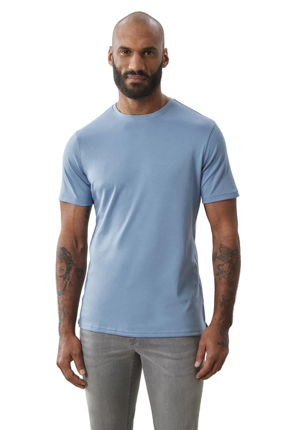 Man wearing a light blue t-shirt and gray pants on a plain background