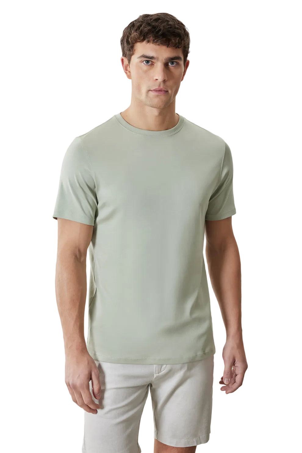 Man wearing a light green t-shirt and beige shorts on a plain background